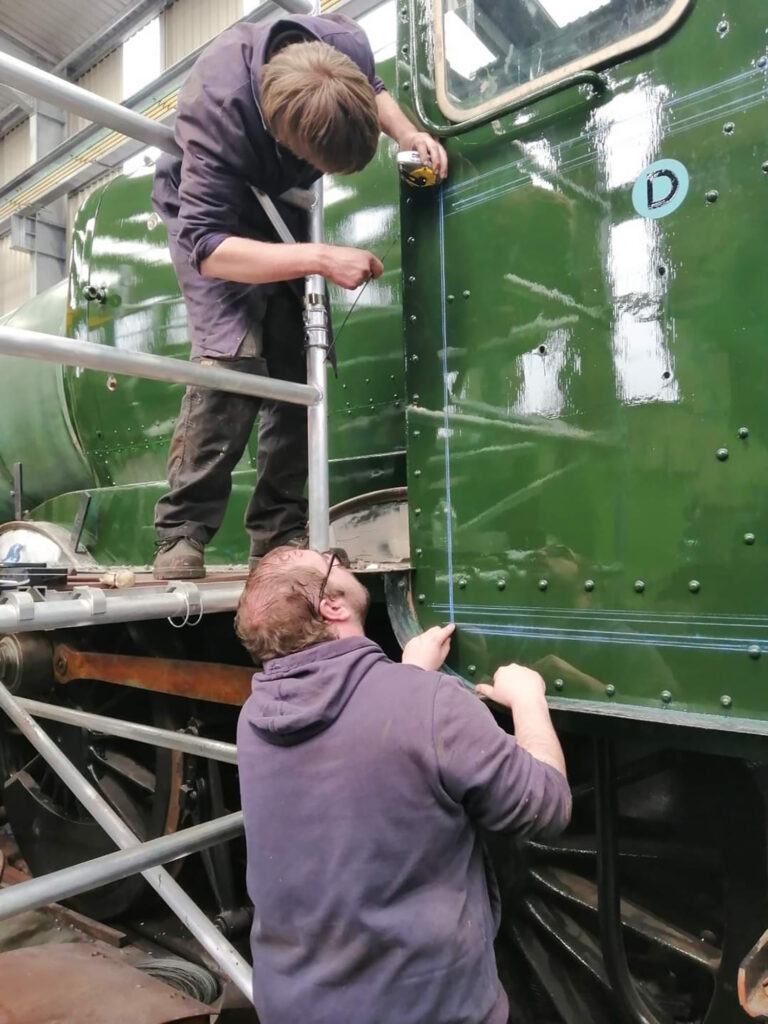 On 30th April, painter Scott Barnes prepares the fireman’s cab side for lining out, assisted by West Somerset Railway volunteer Duncan Hensley [Photo: Terry Jenkins]: